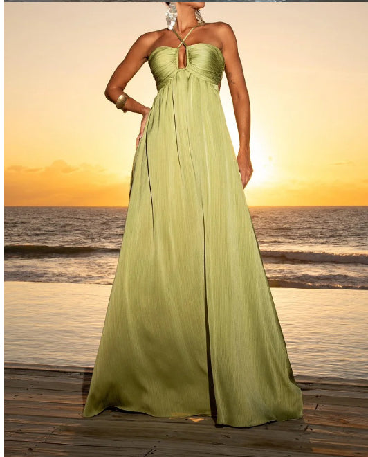 Model posing on a beach at sunset in a green satin summer maxi dress.