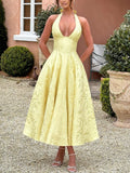 Model wearing a yellow A-line halter midi dress for a garden party