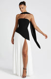 Woman wearing a black and white color block strapless maxi dress with a thigh-high slit.