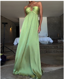 Woman wearing a flowy light green halter maxi dress with a keyhole bust detail.